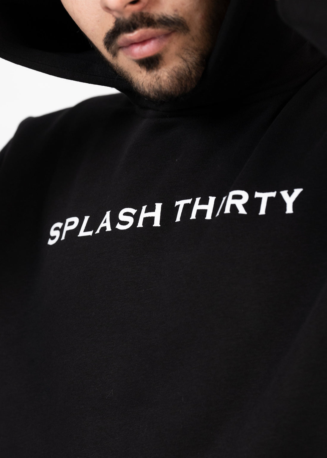 A male model wearing a black hoodie with the text 'Splash Thirty' printed on the front.