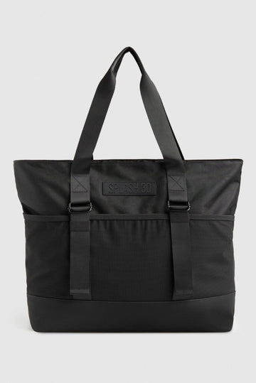 Black tote bag with a visible brand logo on a light gray background.