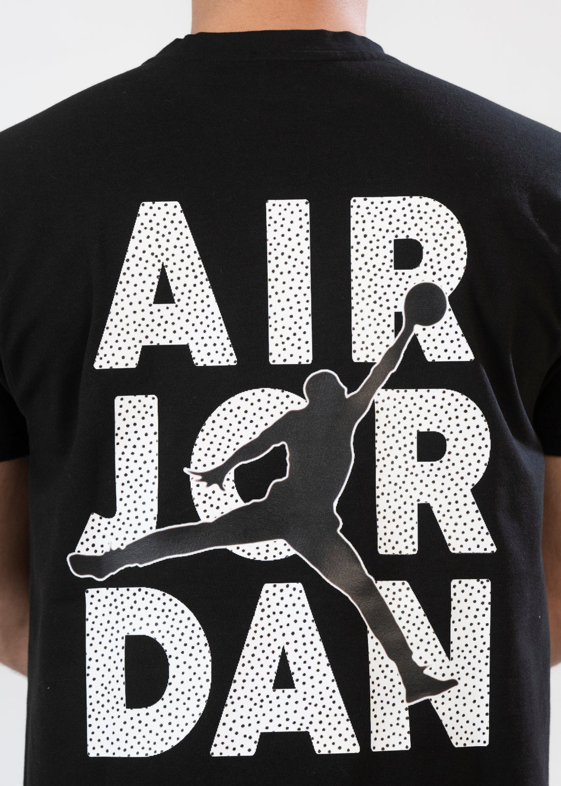 A male model wearing a black t-shirt with 'Air Jordan' text printed on the back.