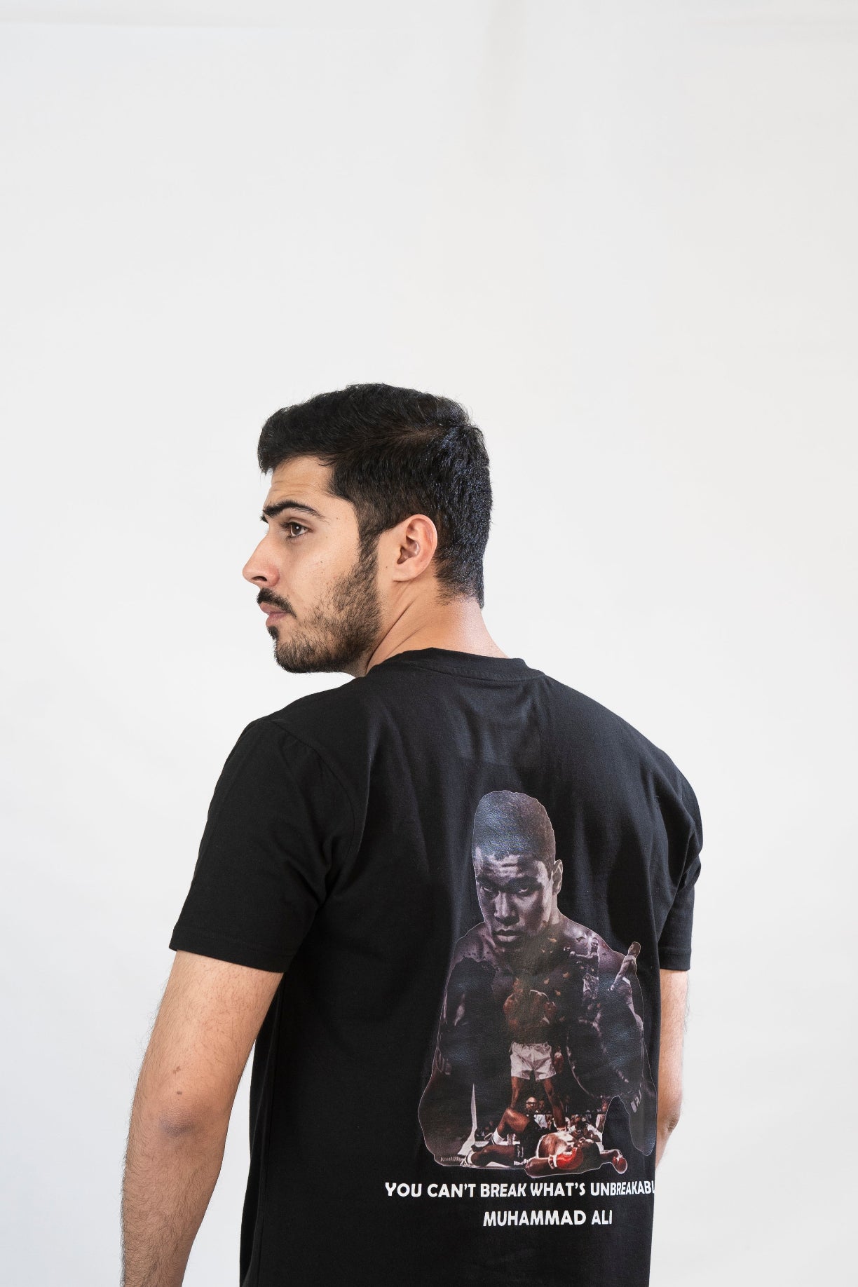 Man wearing a black t-shirt with a graphic design on the back against a white background
