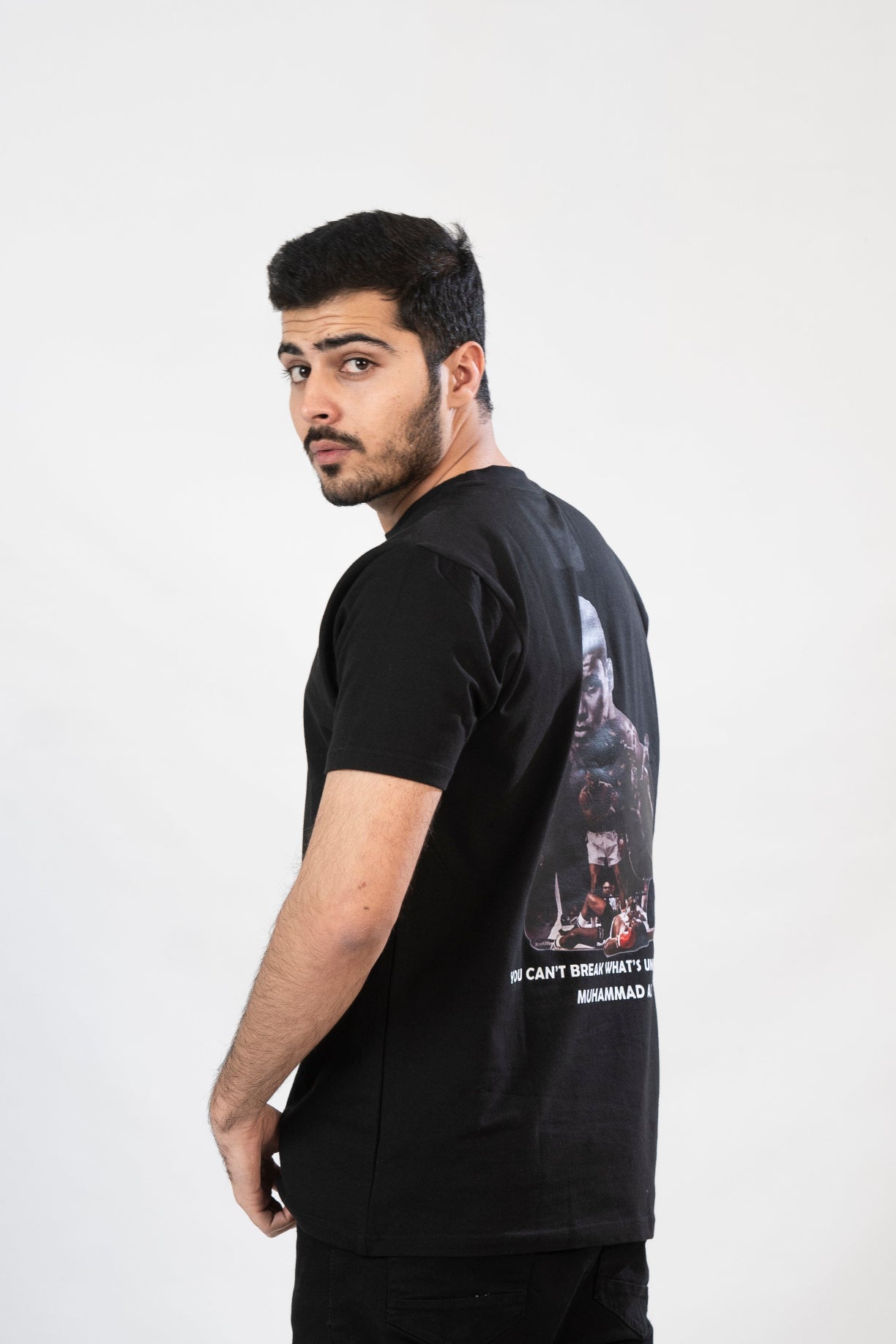 Man wearing a black t-shirt with graphic design on the back against a white background
