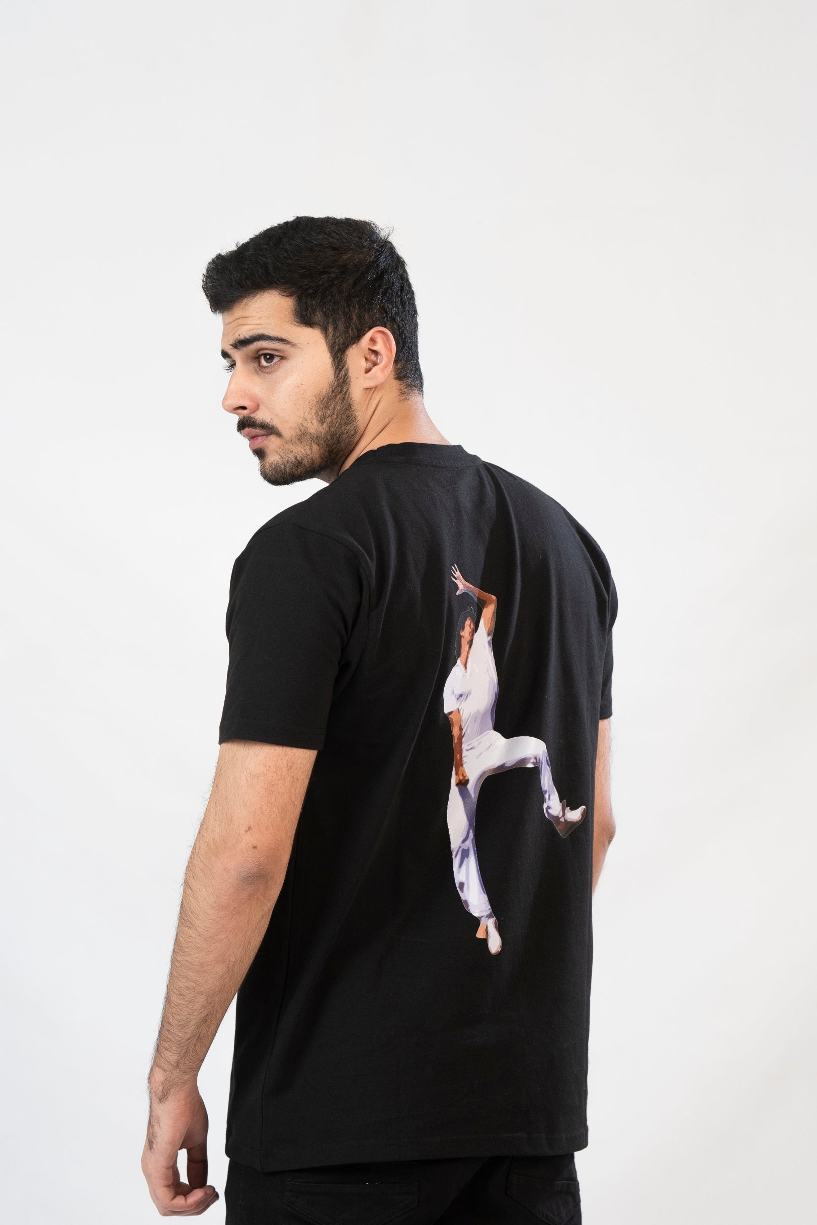 Man wearing a black t-shirt with a graphic design on the back against a white background
