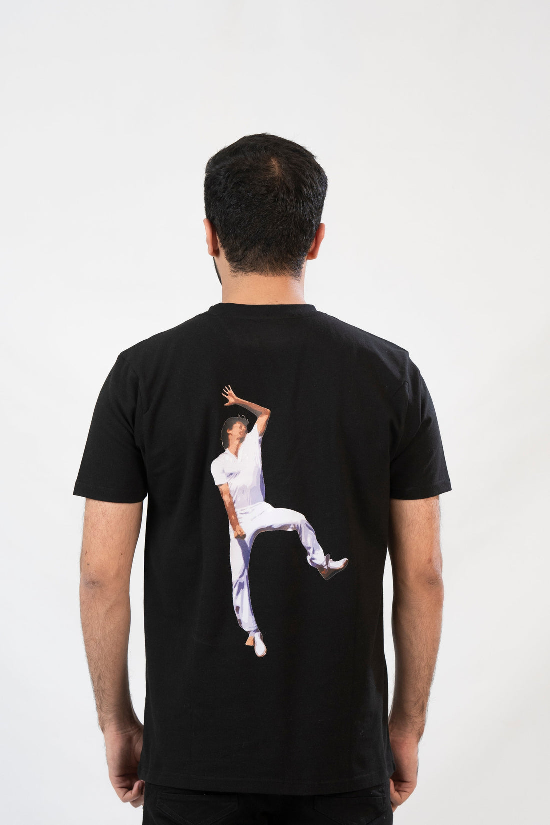 Man wearing a black t-shirt with a graphic design on the back against a white background