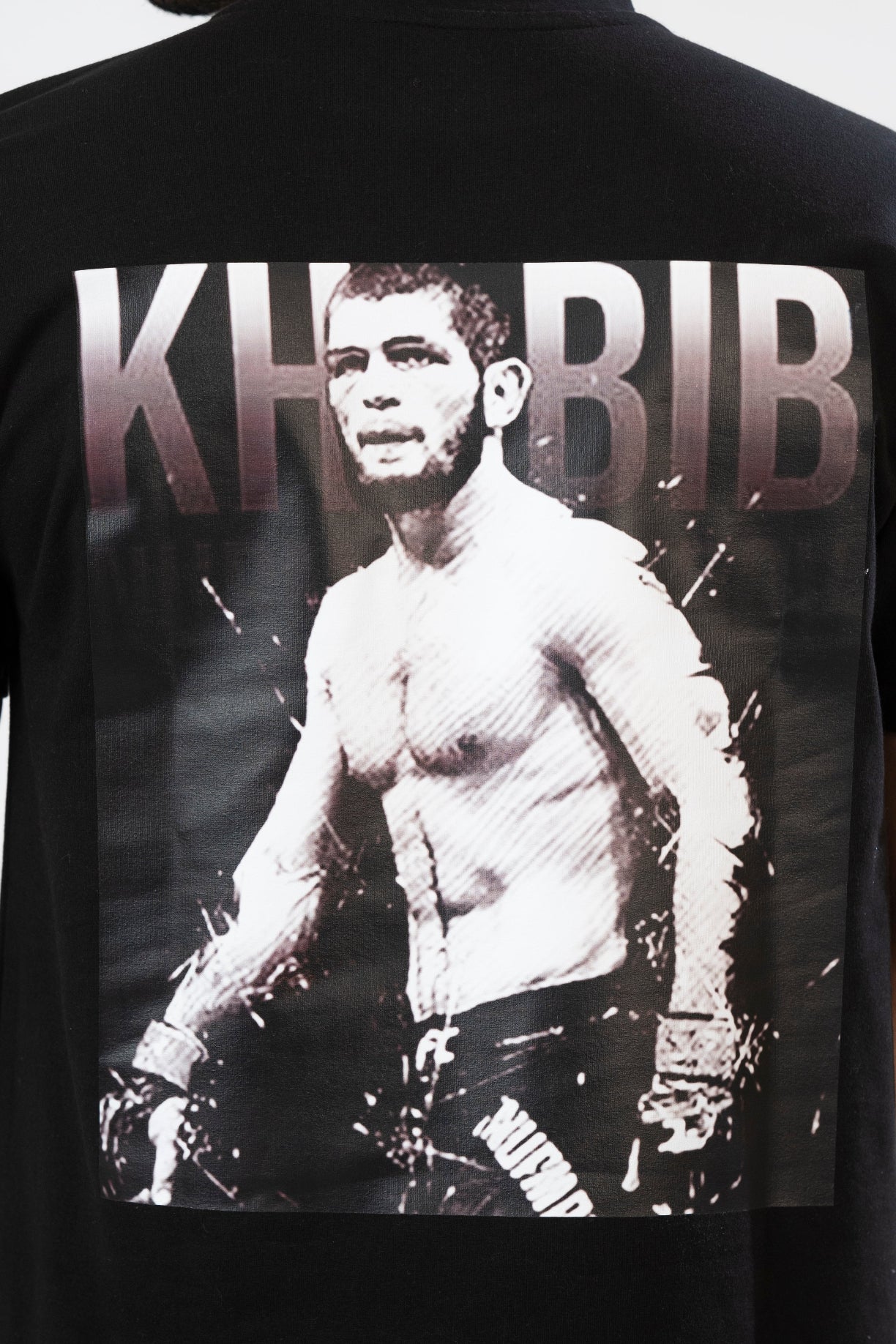 Black t-shirt with a graphic of a shirtless man and 'KHIBIB' text on the back.