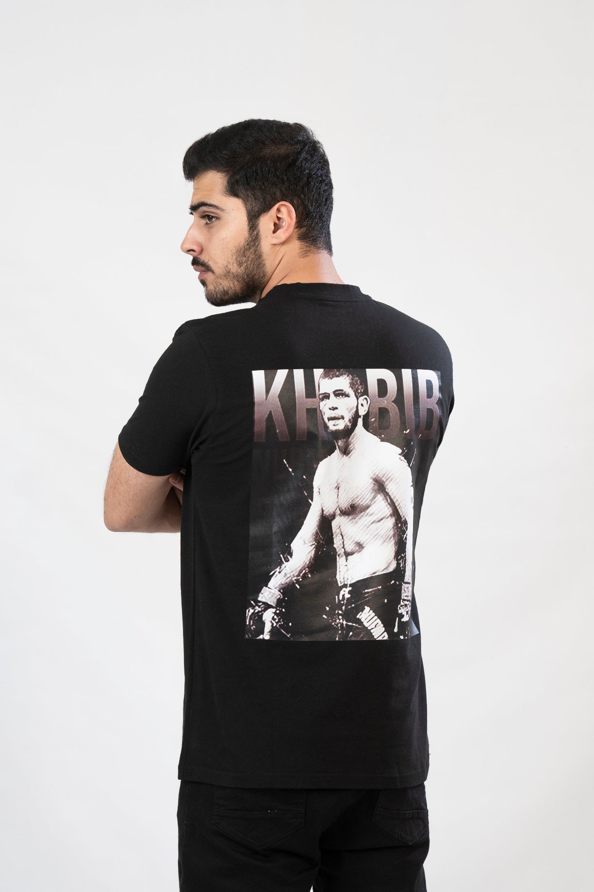 Man wearing a black t-shirt with a graphic of a boxer and the word 'KHUR' on the back.