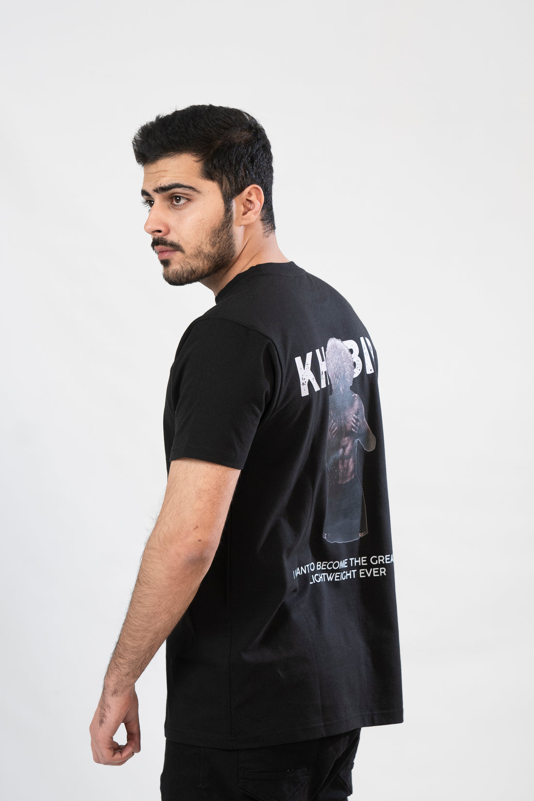 Person wearing a black t-shirt with 'KHOBIB' and graphic design on the back.