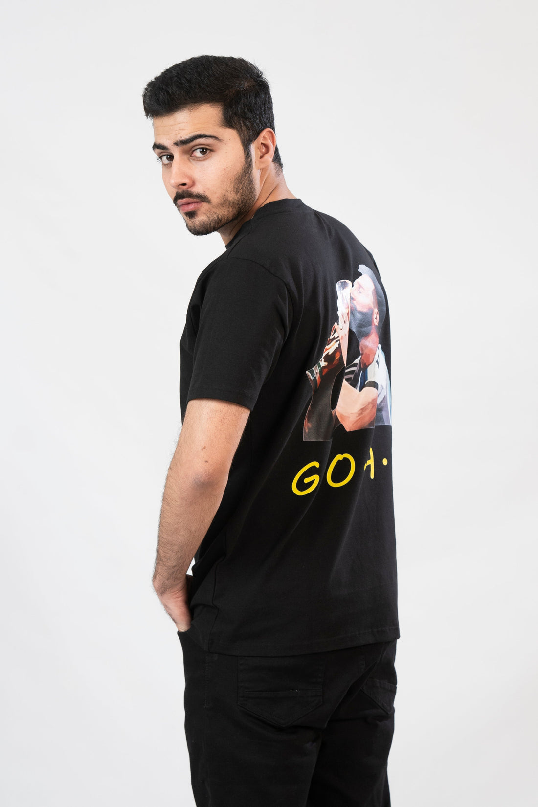 Person wearing a black t-shirt with a graphic and 'G.O.A.T.' text on the back.