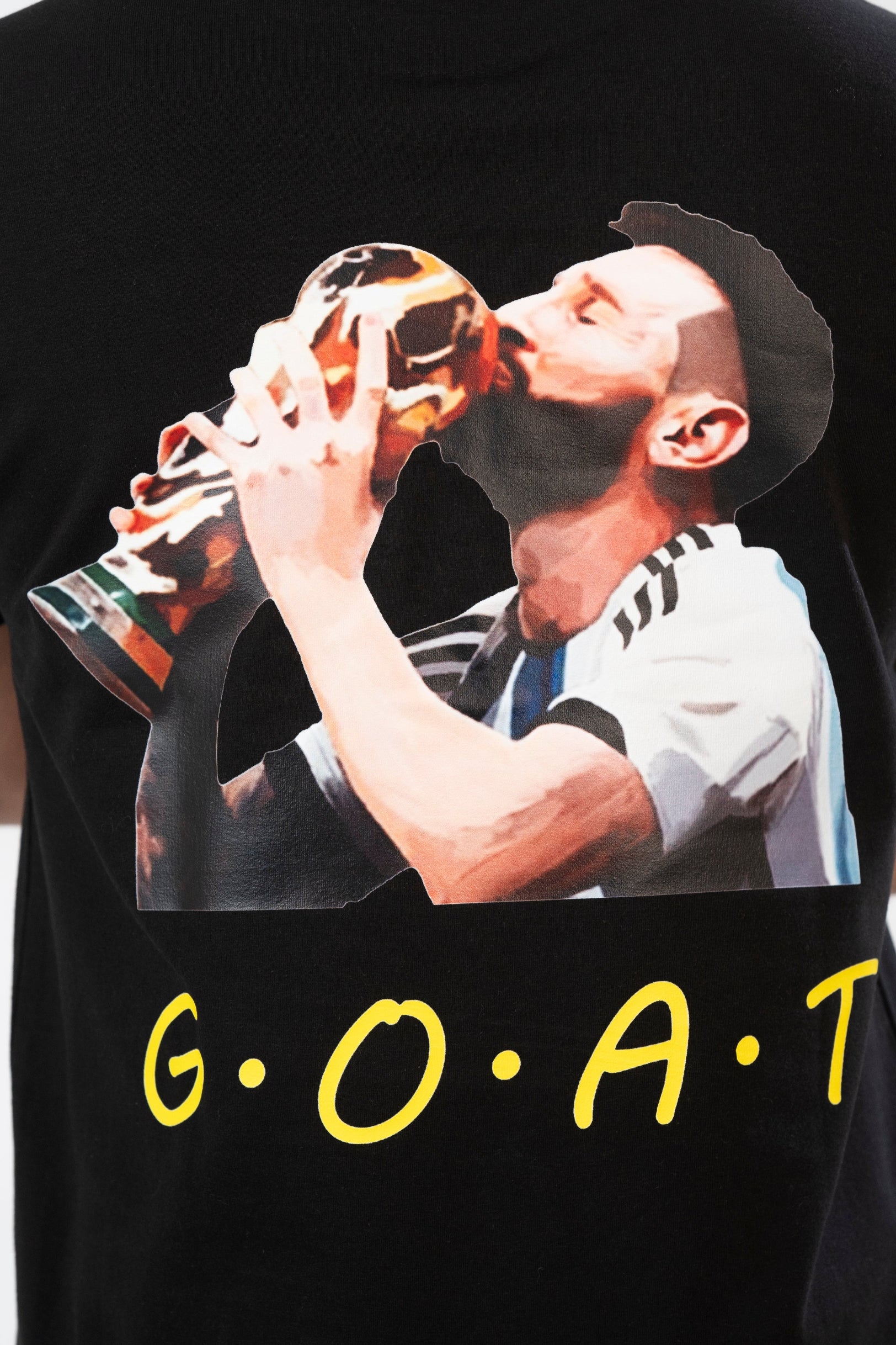 Black t-shirt with a graphic of a person kissing a trophy and 'G.O.A.T.' text.