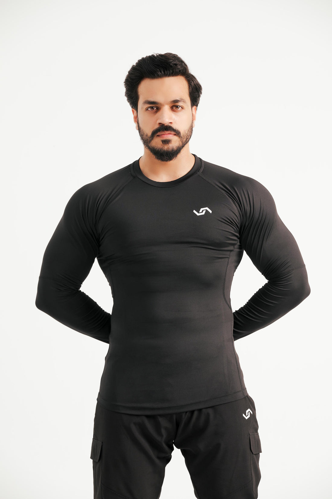 A male model wearing a black long sleeve compression shirt and matching pants, standing against a white background.