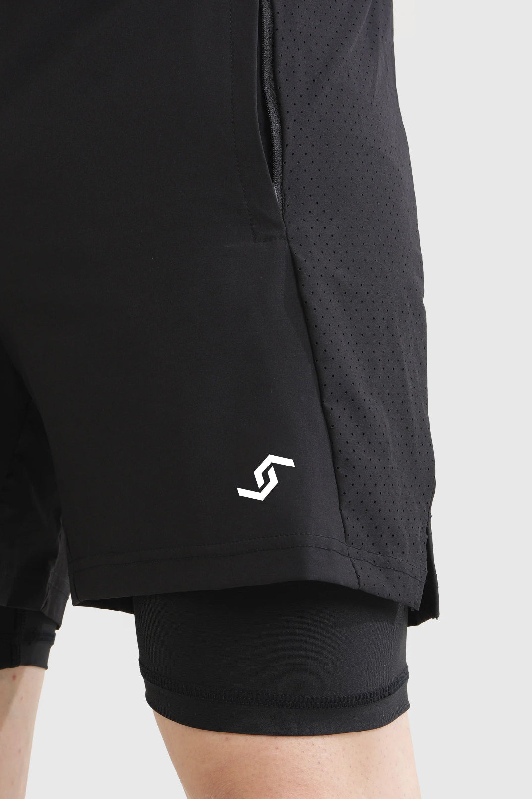 Black athletic shorts with a logo on a light gray background