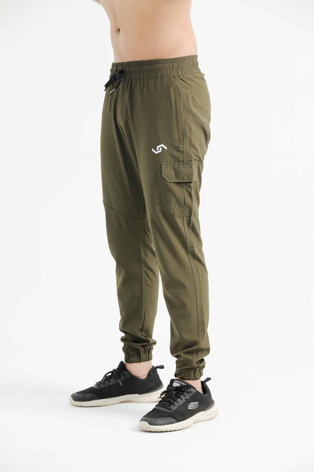 A person standing wearing green cargo pants with elastic bottom cuffs and multiple pockets, paired with a white top and black shoes.