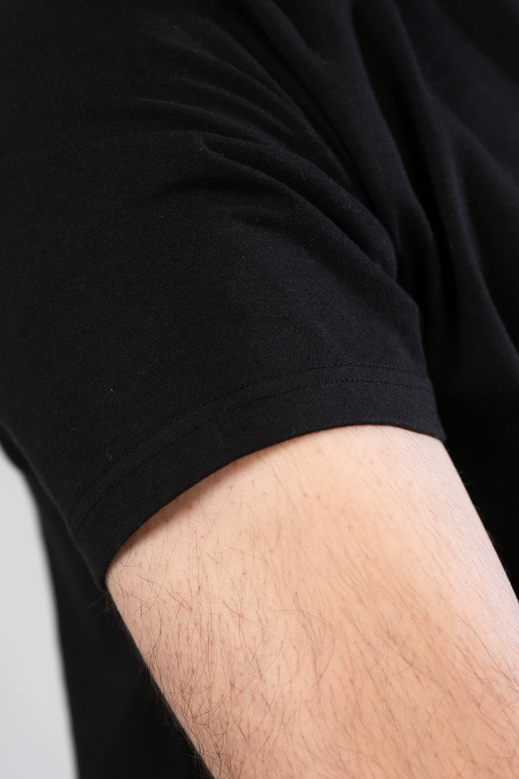 Close-up of a person wearing a black shirt with a focus on the sleeve and arm.