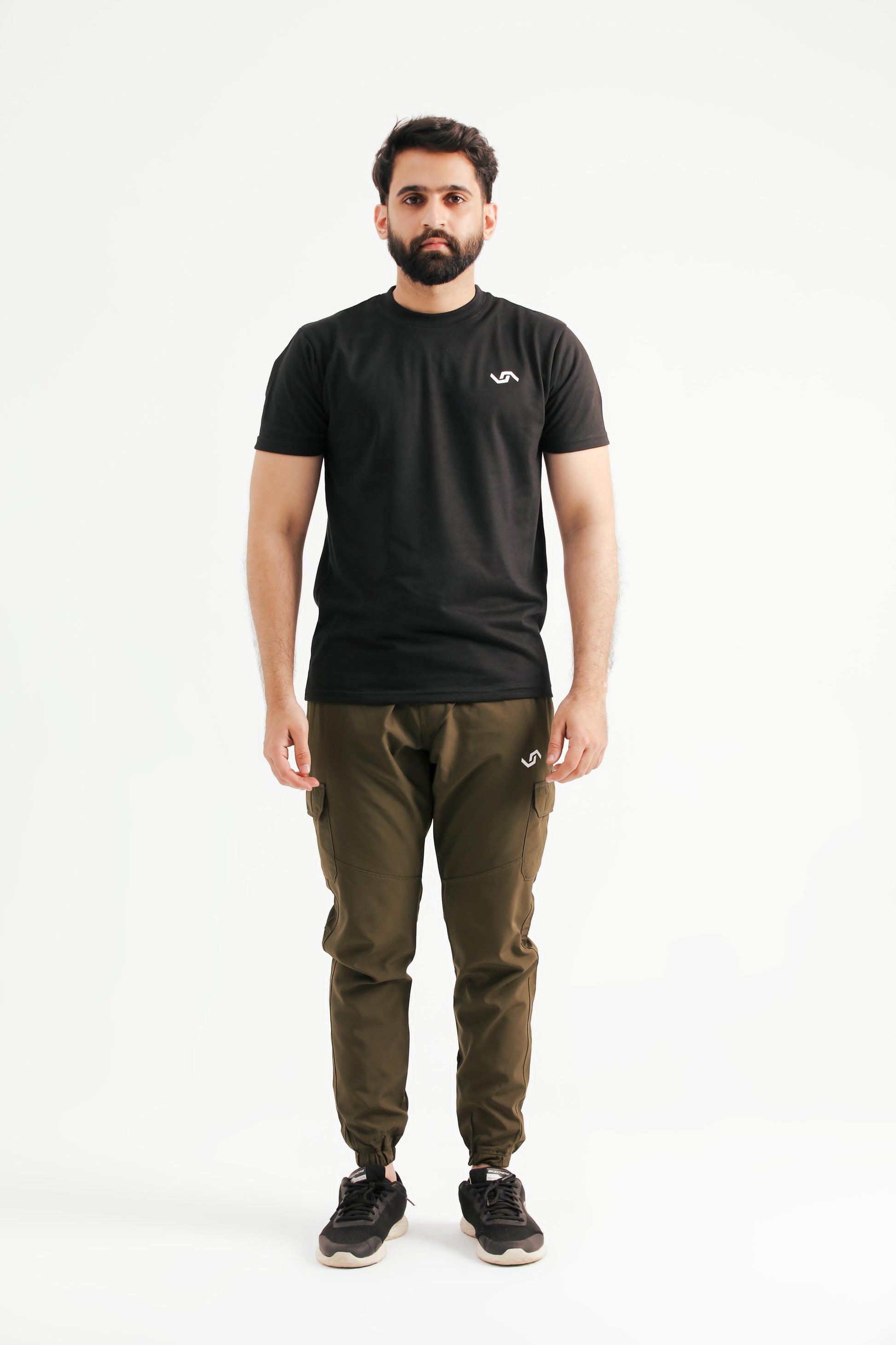 A person standing wearing a black t-shirt and green pants.