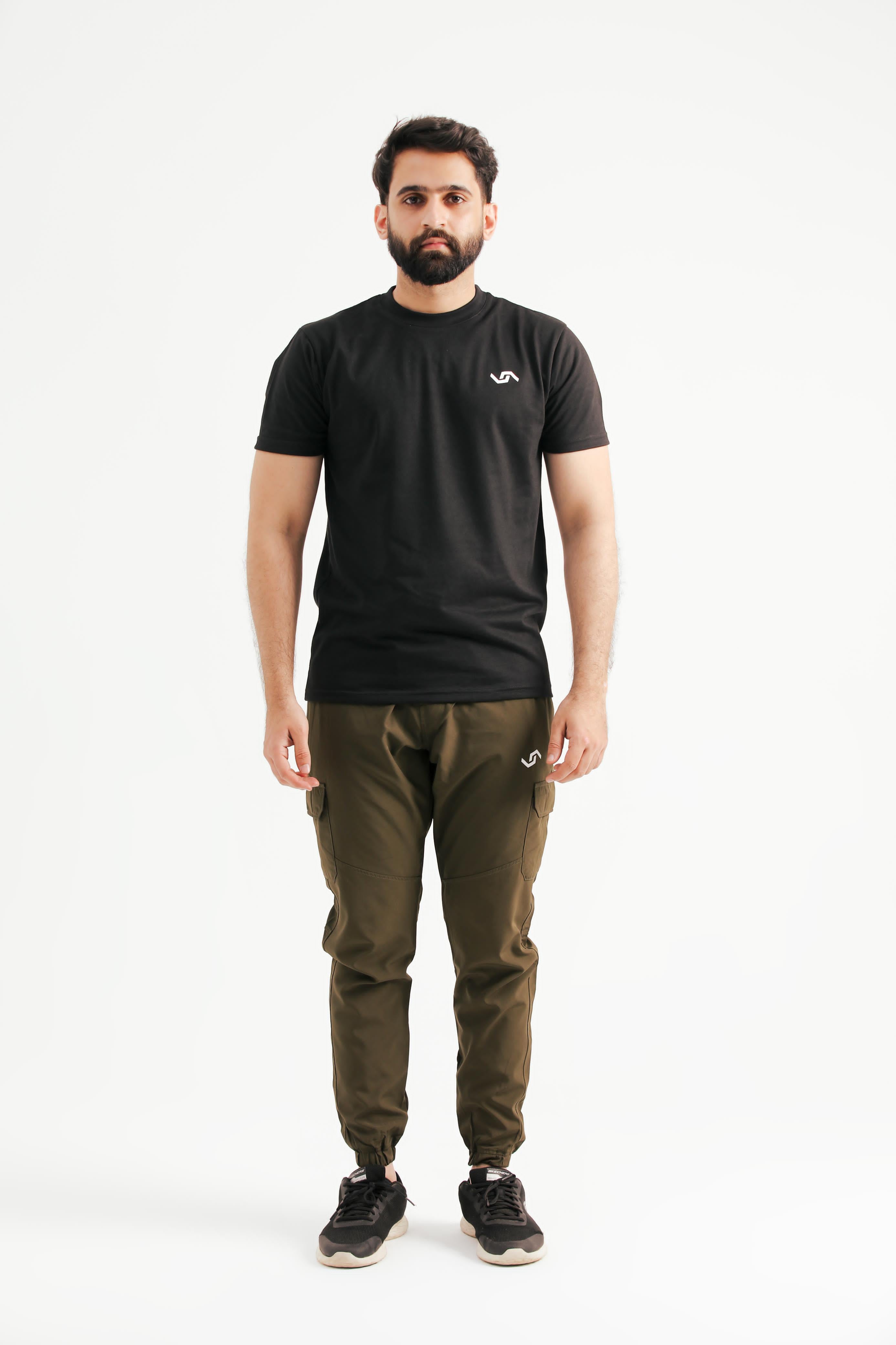 A person standing wearing a black t-shirt and green pants.
