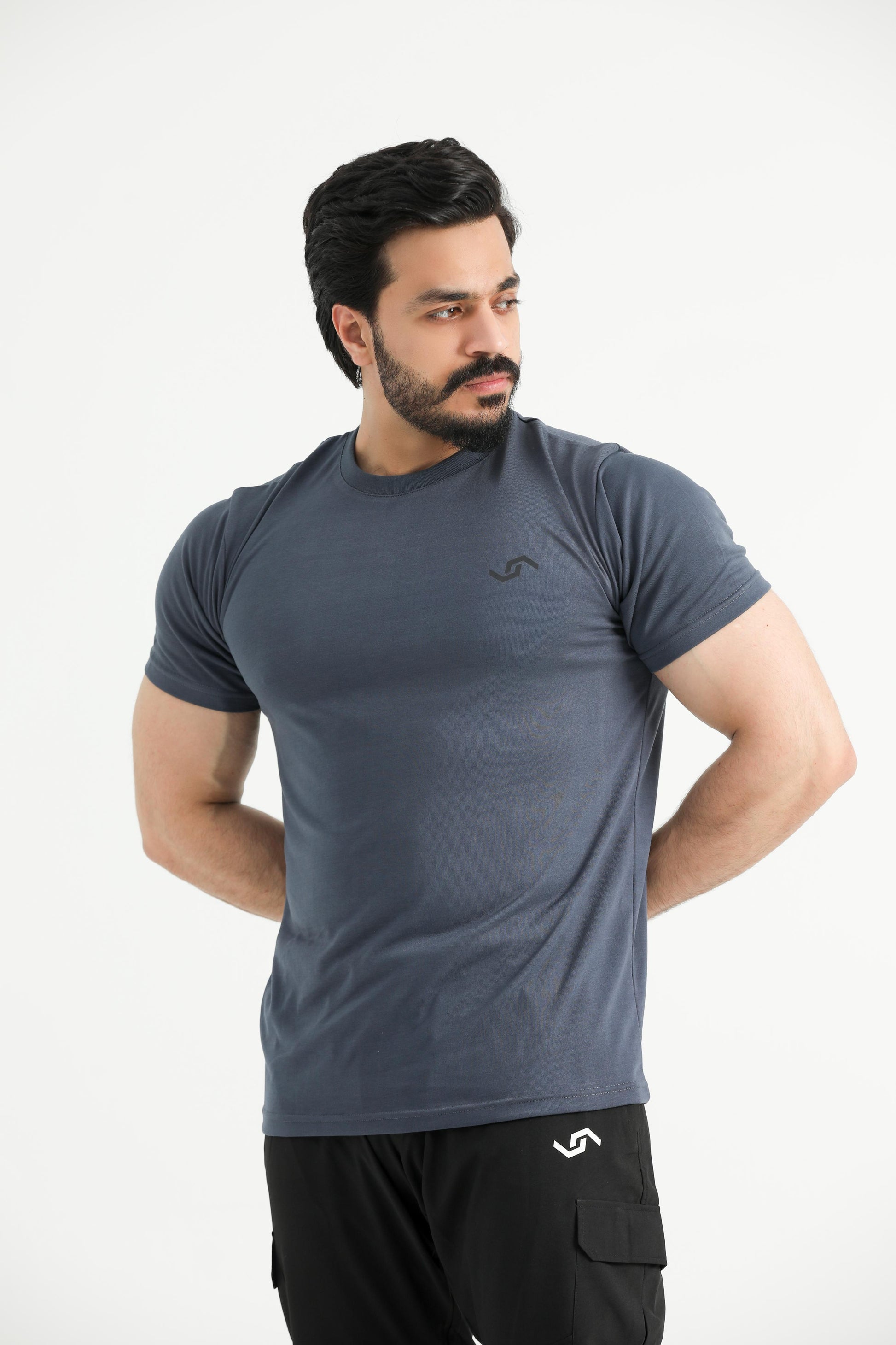 A man wearing a gray t-shirt and black pants. The t-shirt has a round neckline and short sleeves.