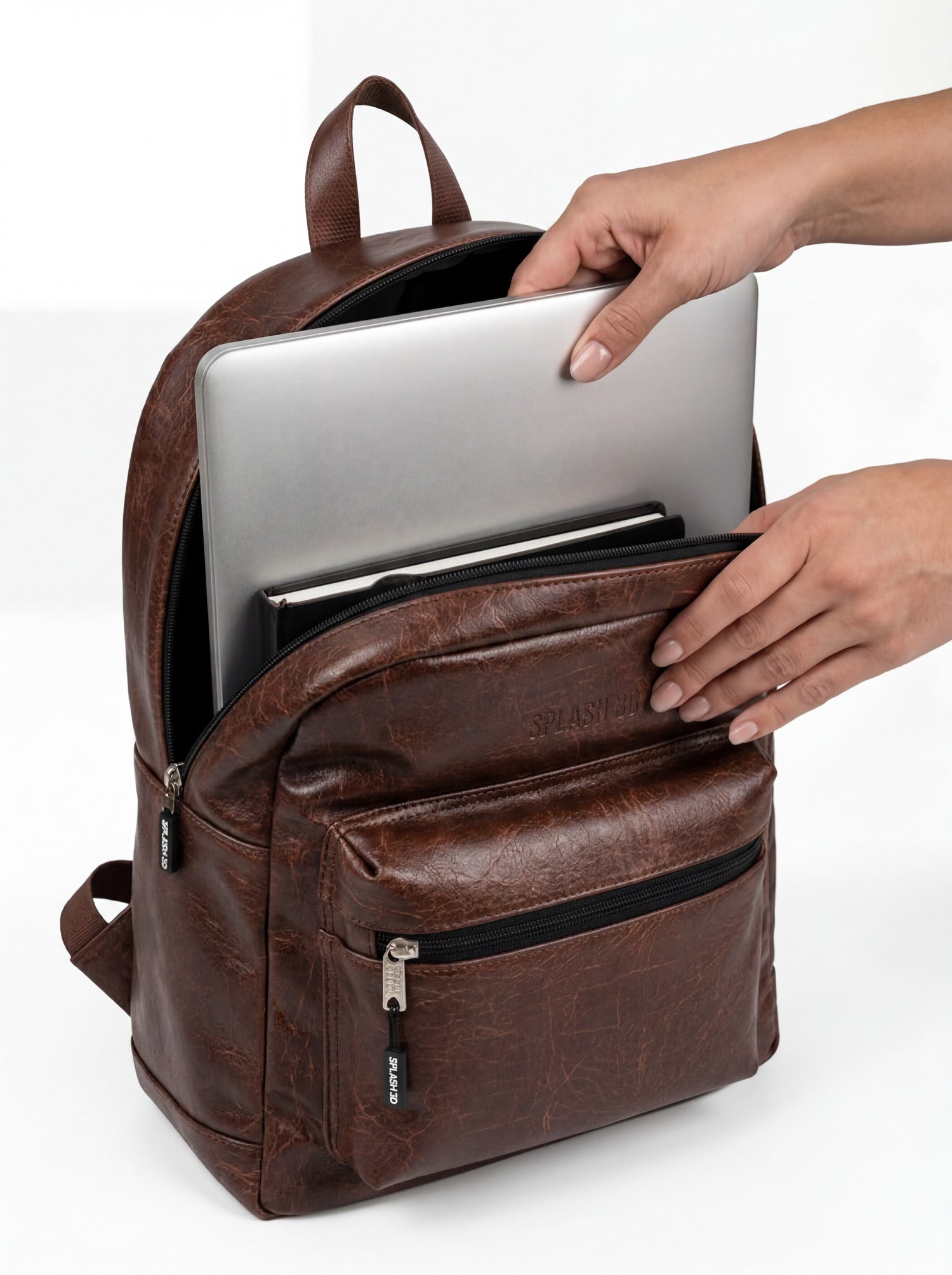 Splash30 Brown Leather Backpack 30L with 16 inch laptop being inserted into dedicated sleeve