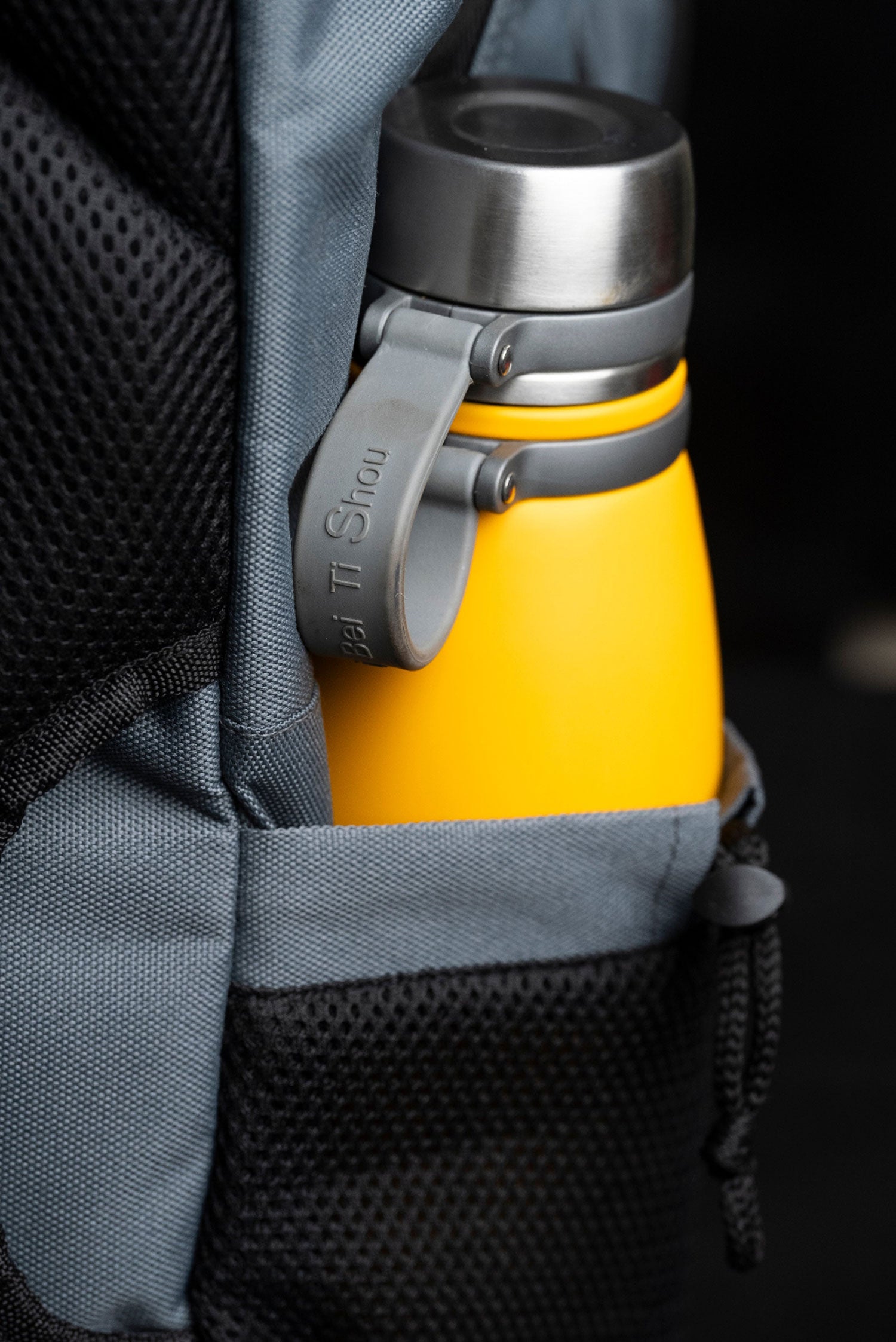 Yellow water bottle held in the side bottle pocket of the gray Splash30 tactical backpack
